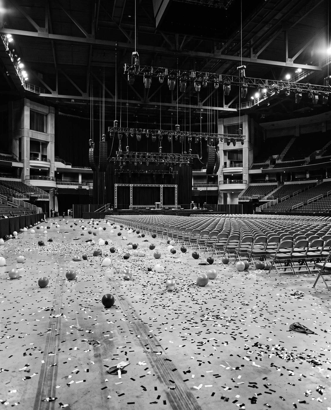 An empty arena floor after a rally, confetti and balloons
